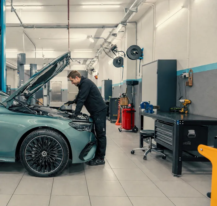 Mechaniker füllt Motoröl bei einer Inspektion in einer hellen Werkstatt nach
